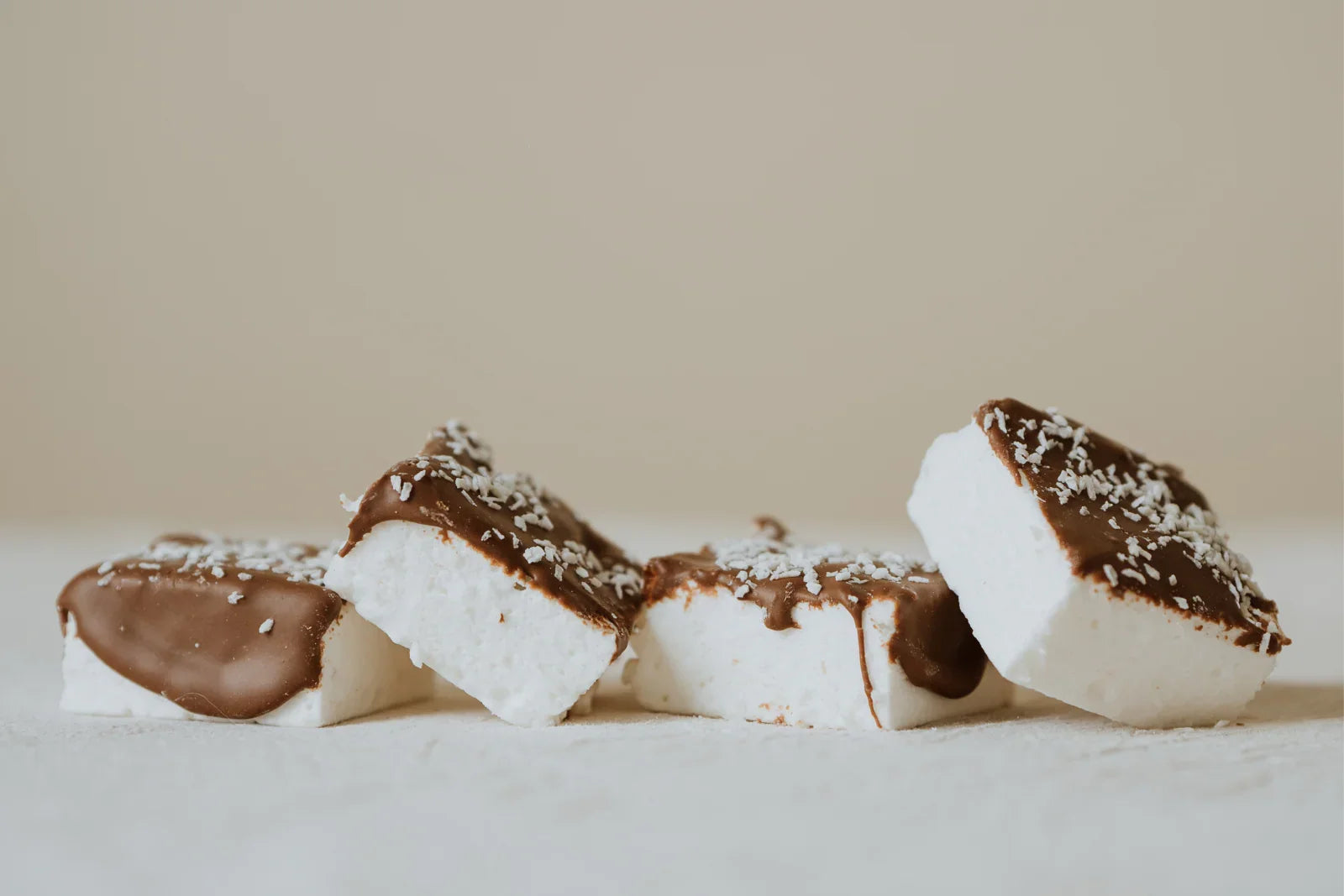 Coconut marshmallows with chocolate and coconut toppings on a light background