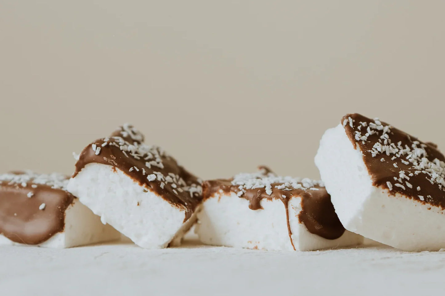 Coconut Marshmallows with chocolate drizzle and coconut flakes on a neutral background
