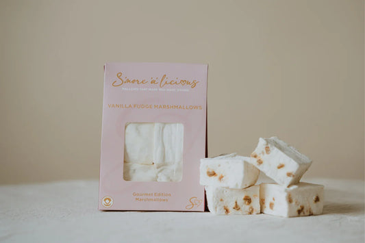 Vanilla marshmallows stuffed with pieces of soft fudge with a pink packaging box on a beige background