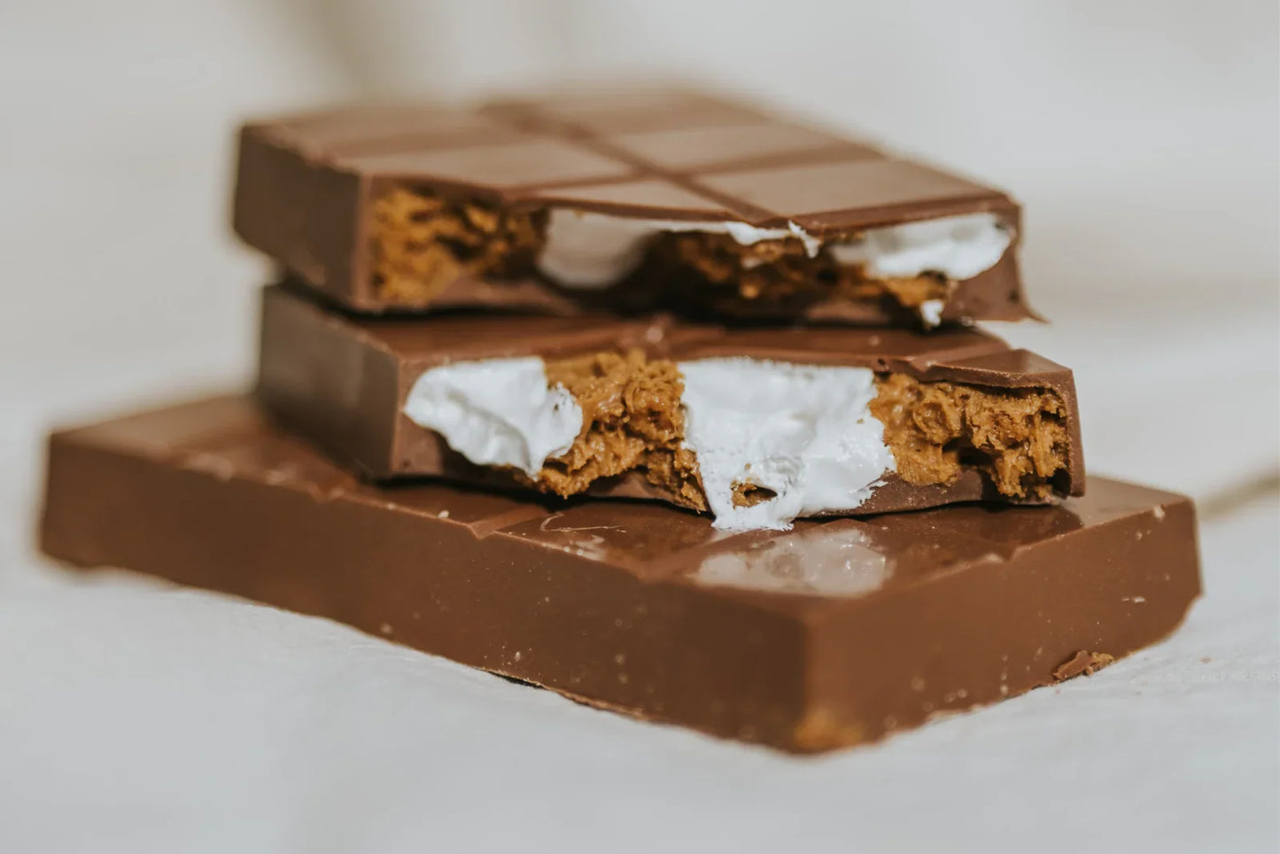Stack of chocolate bars with marshmallow fluff and lotus biscoff filling on a light background