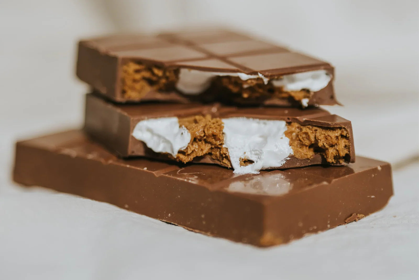 Stack of chocolate bars with marshmallow fluff and lotus biscoff filling on a light background