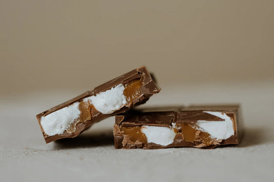 Two chocolate bars with marshmallow fluff and caramel filling on a beige background