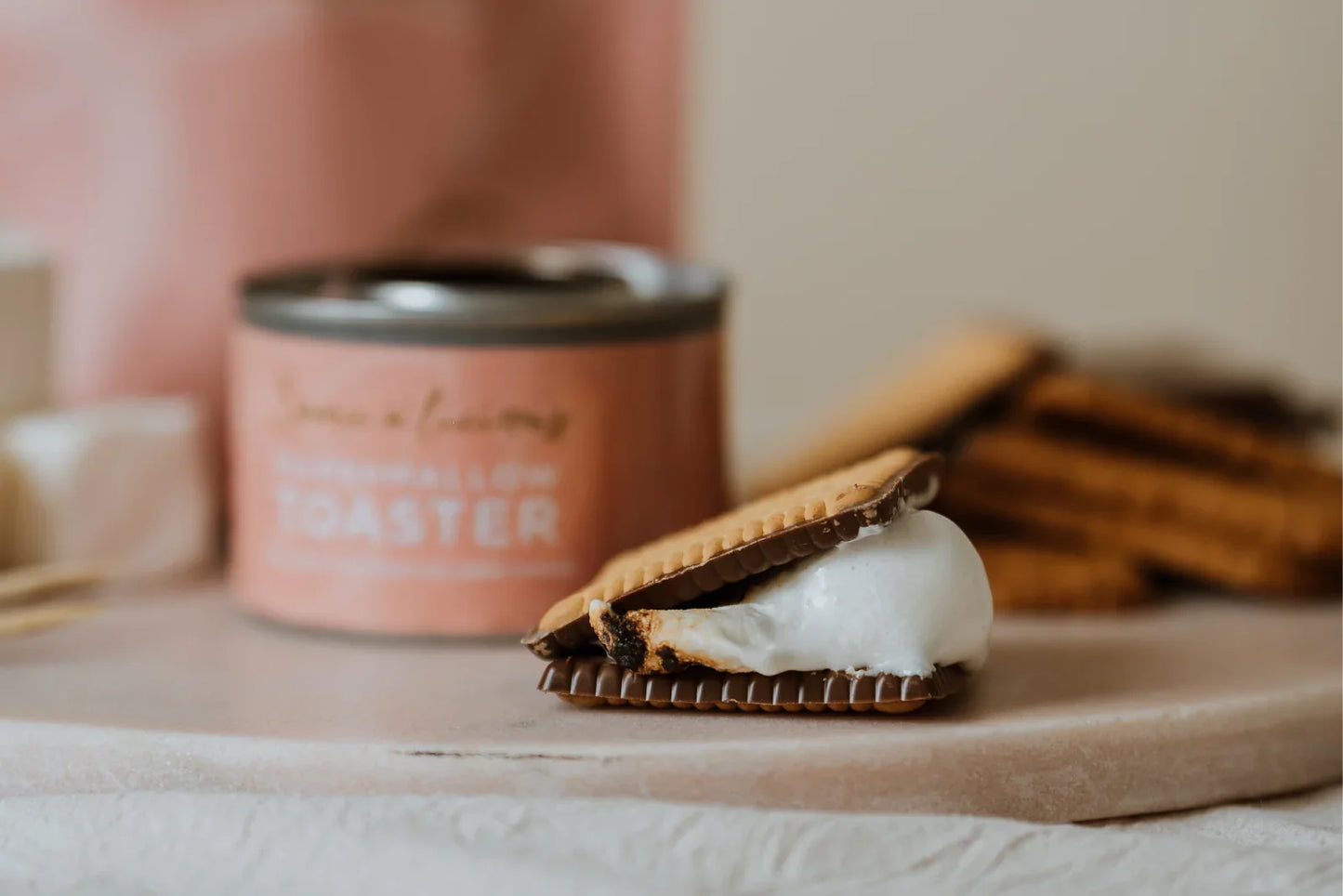 S'mores with a can of marshmallow roaster on a wooden board