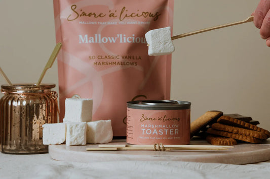 Mallowlicious marshmallow packaging with marshmallows and cookies on a wooden board.